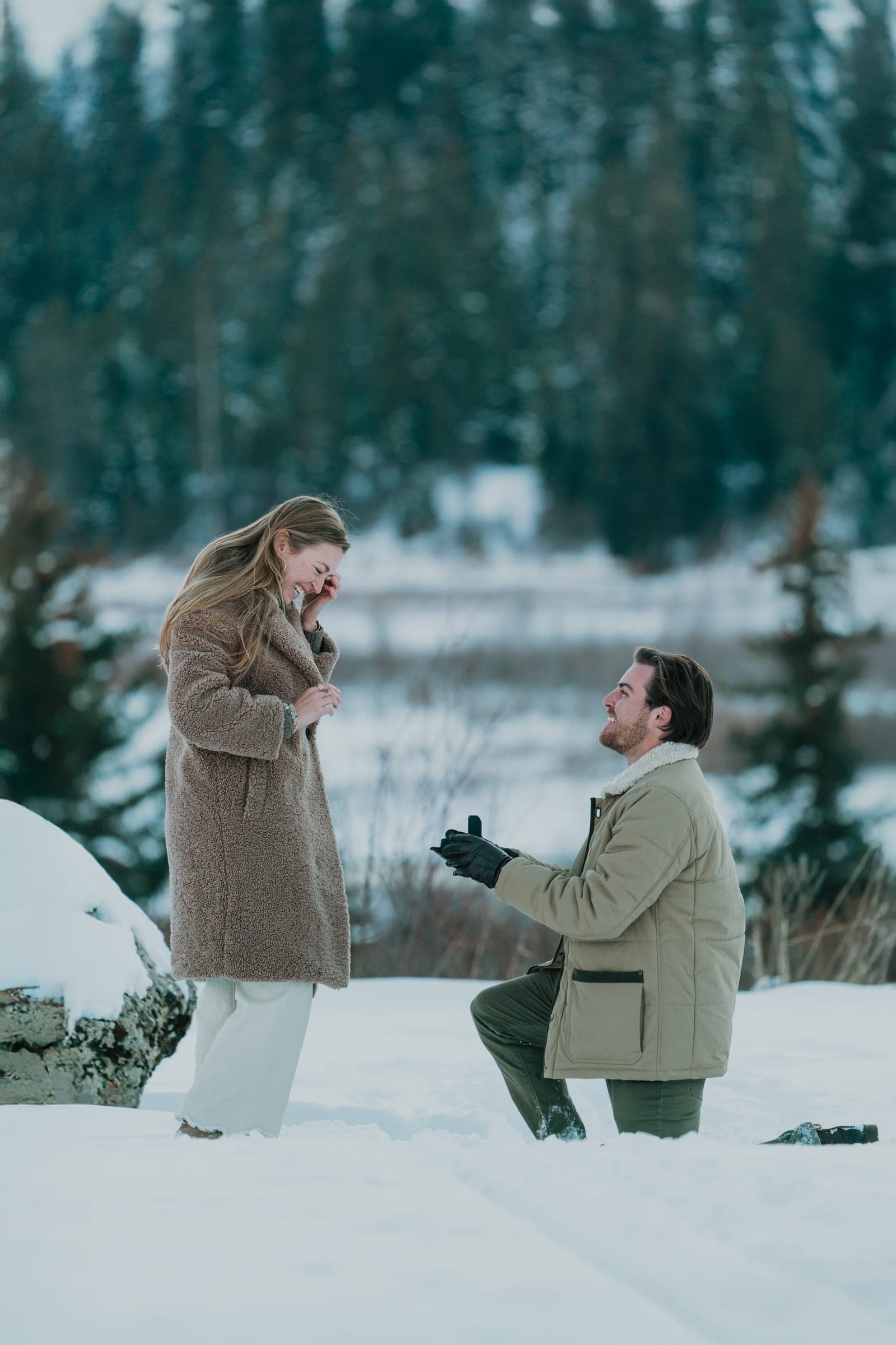 Noah on one knee proposing to Maggie in the snow at Snake River Sporting Club